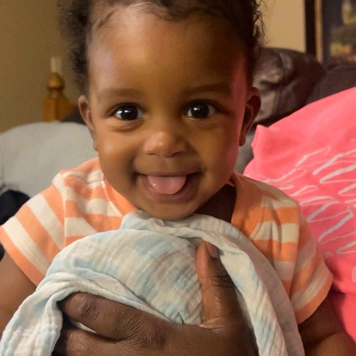 Kaylx is registered to the contest to win money with this photo: baby, blanket, child, closeup, cozy, cute, expression, face, hand, happy, holding, indoor, infant, person, portrait, skin, smiling, striped_clothing, tongue_out, warmth