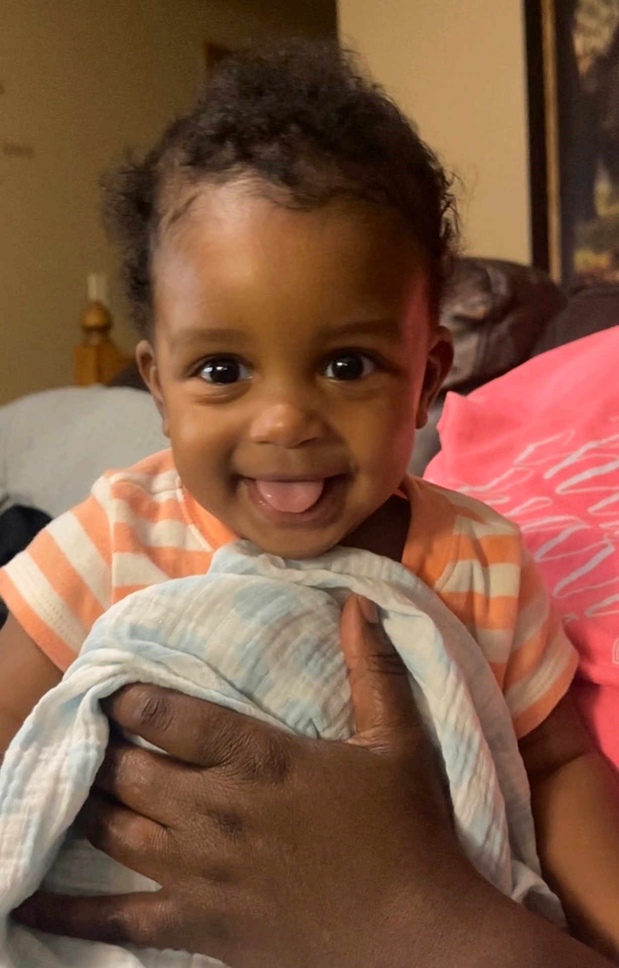 Kaylx is registered to the contest to win money with this photo: baby, child, smiling, tongue_out, blanket, hand, indoor, person, cute, portrait, striped_clothing, happy, infant, skin, face, holding, warmth, cozy, expression, closeup