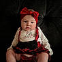 baby, child, couch, cute, festive, headband, holiday, indoor, infant, plush, portrait, pout, red_bow, red_plaid, seated, skirt, socks, soft_lighting, white_top, young