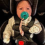 Rayliana is registered to the contest to win money with this photo: baby, car_seat, pacifier, headband, mittens, white_sweater, black_pants, child, infant, safety_harness, cute, portrait, indoors, seat_belt, red_button, clothing, face, person, young_child, baby_accessories