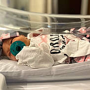 Rayliana joined the competition — help win amazing prizes! newborn, baby, pacifier, blanket, hospital, bassinet, infant, headband, clothing, bed, sleeping, cute, swaddled, pink, white, heart_pattern, closeup, indoor, person, portrait