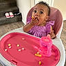 Kimora is registered to the contest to win money with this photo: baby, child, clothing, curly_hair, drink, eating, face, feeding, food, high_chair, indoor, person, pink, shoes, sippy_cup, snack, stairs, table, toddler, wood_floor