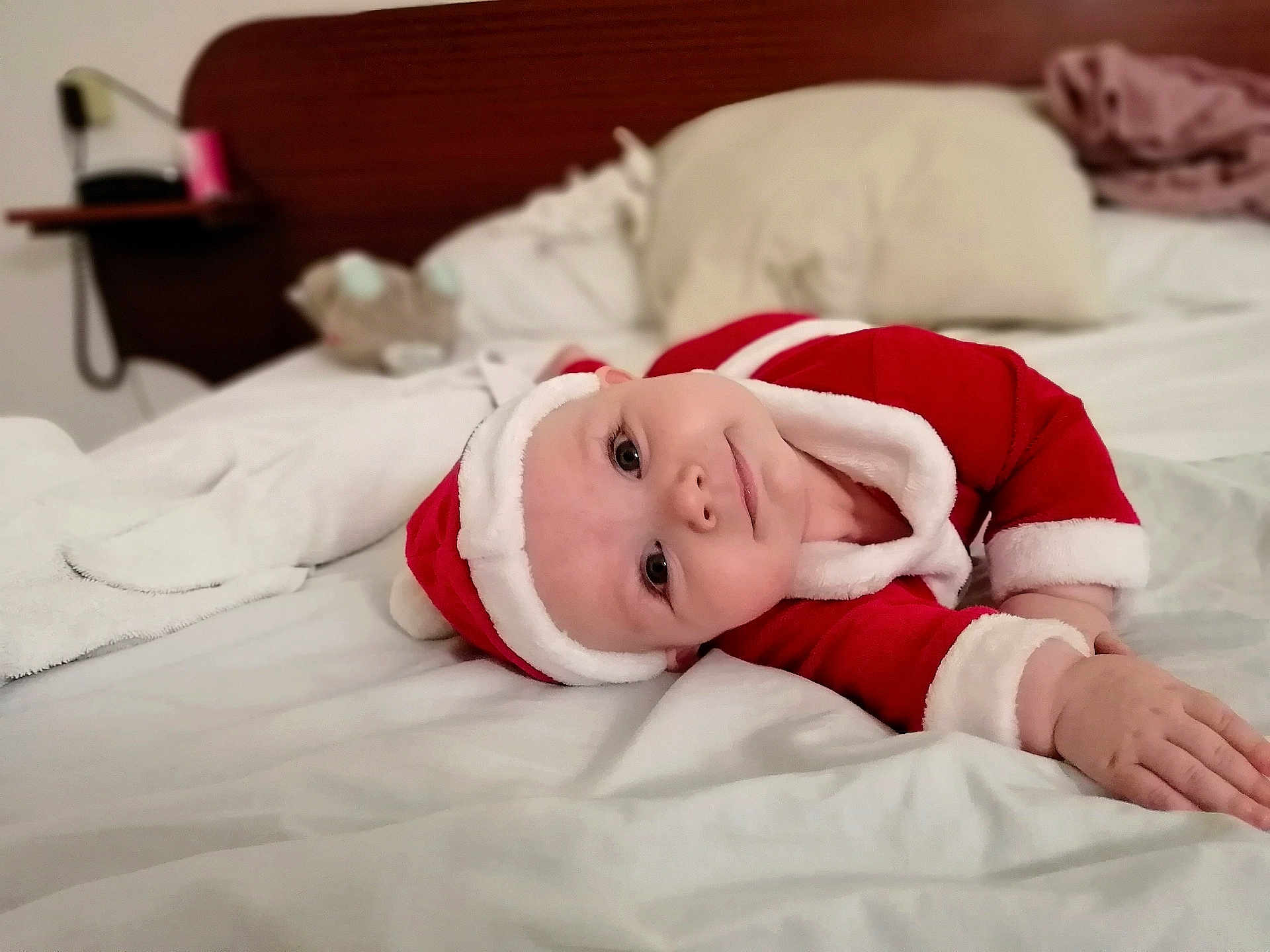 Phœbe a rejoint le concours — aidez-le/la à gagner de superbes lots ! baby, child, santa_outfit, bed, blanket, pillow, indoors, cute, lying_down, face, infant, holiday, christmas, soft_texture, smiling, red_clothing, white_trim, head_tilt, cozy, sleepwear