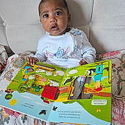 Teeian joined the competition — help win amazing prizes! baby, child, book, reading, bed, onesie, floral_pattern, indoor, curious, wide_eyes, colorful, illustration, storybook, hand, face, portrait, seated, young_child, expression, cozy
