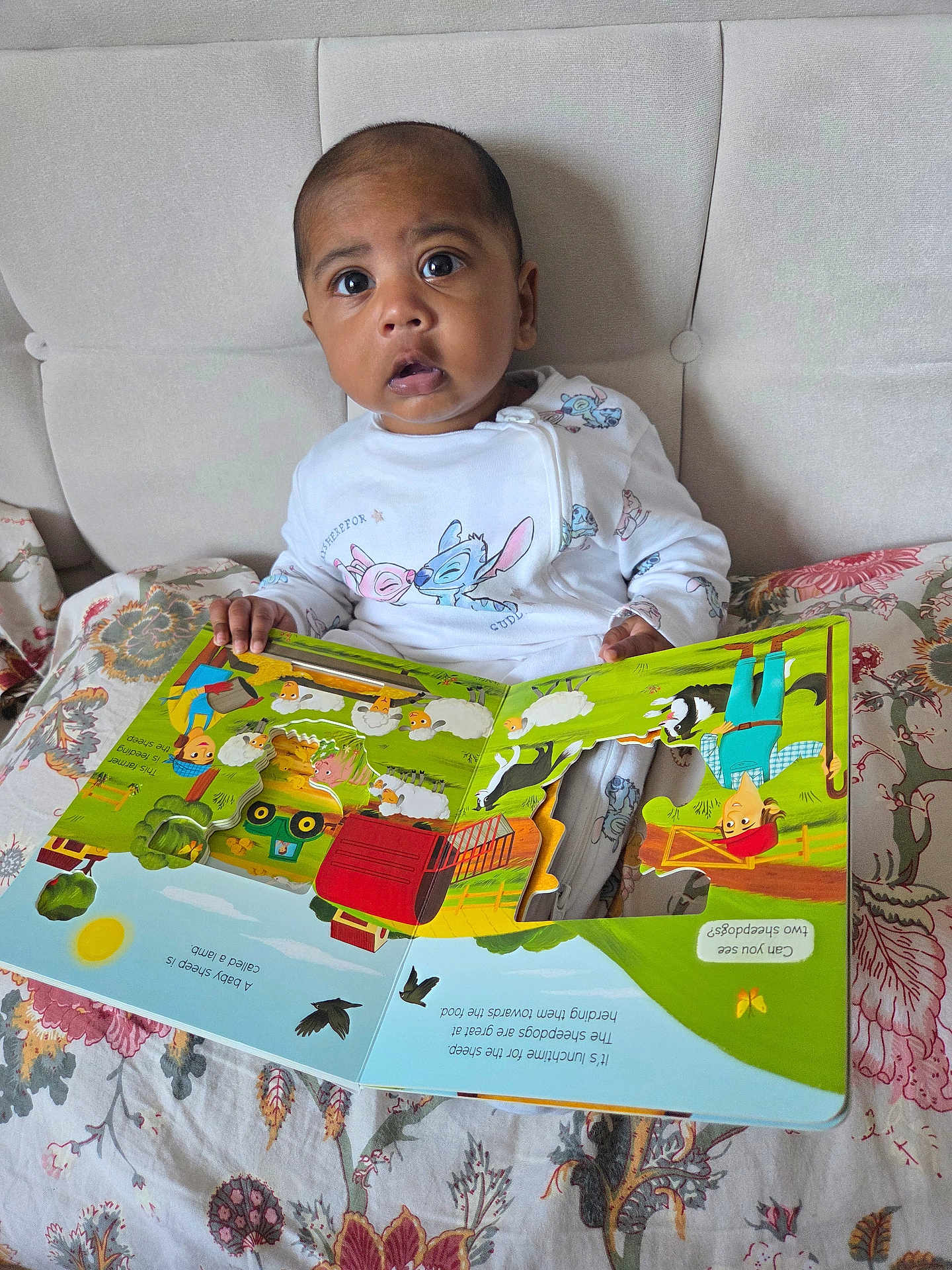 Teeian joined the competition — help win amazing prizes! baby, child, book, reading, bed, onesie, floral_pattern, indoor, curious, wide_eyes, colorful, illustration, storybook, hand, face, portrait, seated, young_child, expression, cozy
