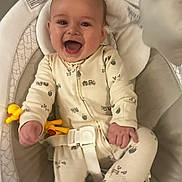 Chayce is registered to the contest to win money with this photo: baby, infant, smiling, laughing, onesie, toy, yellow_toy, baby_seat, safety_belt, cute, happy, child, indoor, cushion, face, hands, feet, clothing, playful, portrait