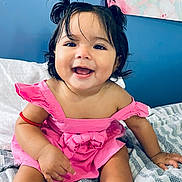 Aurora is registered to the contest to win money with this photo: baby, child, smiling, pink_dress, pigtails, socks, bed, blanket, happy, indoor, portrait, cute, toddler, hair, skin, person, face, room, cozy, infant