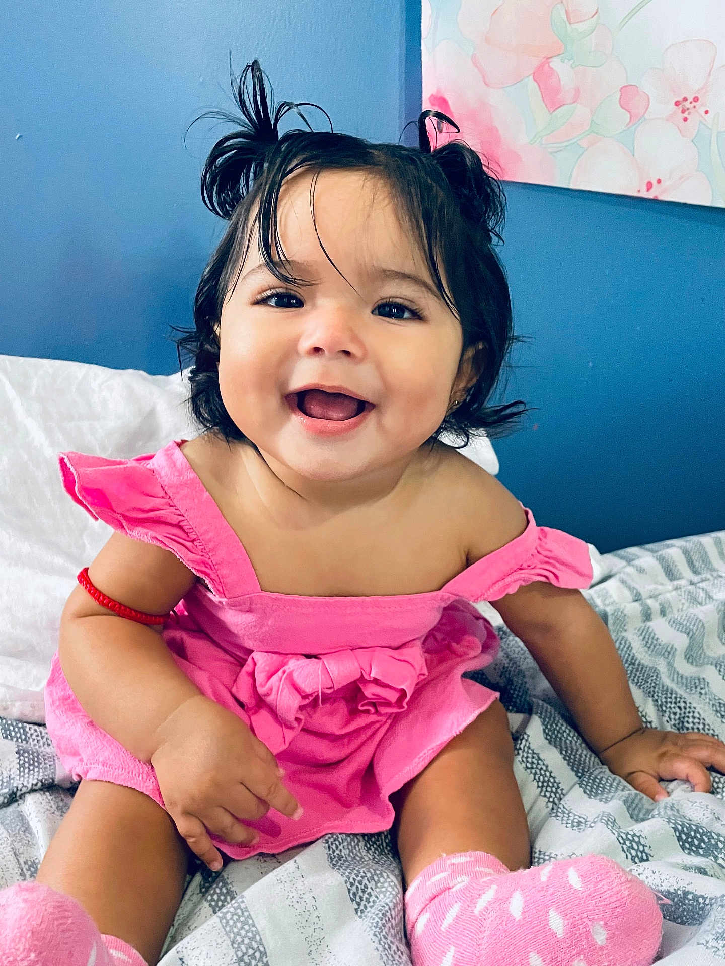 Aurora is registered to the contest to win money with this photo: baby, child, smiling, pink_dress, pigtails, socks, bed, blanket, happy, indoor, portrait, cute, toddler, hair, skin, person, face, room, cozy, infant