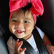 Aurora joined the competition — help win amazing prizes! baby, child, smile, headband, pink_bow, car_seat, seatbelt, infant, happy, face, hand, white_shirt, cute, black_hair, portrait, closeup, young_child, skin, person, indoors