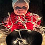 baby, child, face, headband, bow, christmas_lights, red_clothing, black_leggings, blanket, toddler, indoor, festive, glowing_lights, smiling, cute, holiday, portrait, sitting, hands, cozy