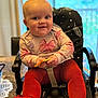 baby, child, high_chair, red_tights, floral_shirt, smiling, indoor, table, snack, curly_hair, happy, seated, furniture, cute, face, person, home, cozy, bright_eyes, infant