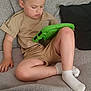 Reggie is registered to the contest to win money with this photo: blanket, casual_clothing, child, couch, curly_hair, cushion, focused, furniture, home, indoor, leisure, relaxing, seated, shorts, skin, socks, tablet, technology, tshirt, young_boy