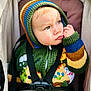 toddler, child, knitted_hoodie, blue_eyes, stroller, seatbelt, colorful_clothing, portrait, baby, cute, outdoor, warm_clothing, hand_on_face, thoughtful, small_fist, closeup, person, face, expression, soft_light
