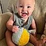 Sonny is registered to the contest to win money with this photo: baby, child, smiling, blue_eyes, plush_ball, armchair, indoor, happy, cute, sitting, barefoot, infant, toy, fabric, texture, person, portrait, young_child, casual_clothing, home