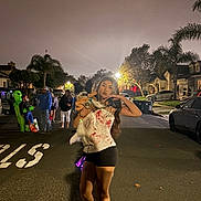Ellie Carlon joined the competition — help win amazing prizes! woman, dog, street, night, costume, halloween, alien_costume, people, suburban, trees, car, streetlight, pavement, posing, black_shorts, long_hair, casual_shoes, group, festive, outdoor