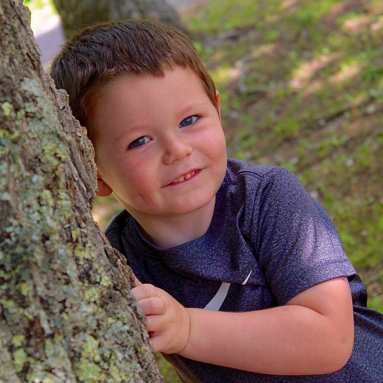 Caleb is registered to the contest to win money with this photo: bodypart, boy, child, clothing, dress, eveningdress, face, finger, hand, happy, head, hiding, male, person, photography, plant, portrait, smile, tree, treetrunk