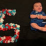 Alessio a rejoint le concours — aidez-le/la à gagner de superbes lots ! baby, birthday, black_background, blue, blue_clothing, celebration, cheerful, child, cute, face, feet, flower_petals, hands, infant, lying_down, number_three, portrait, red, smiling, white