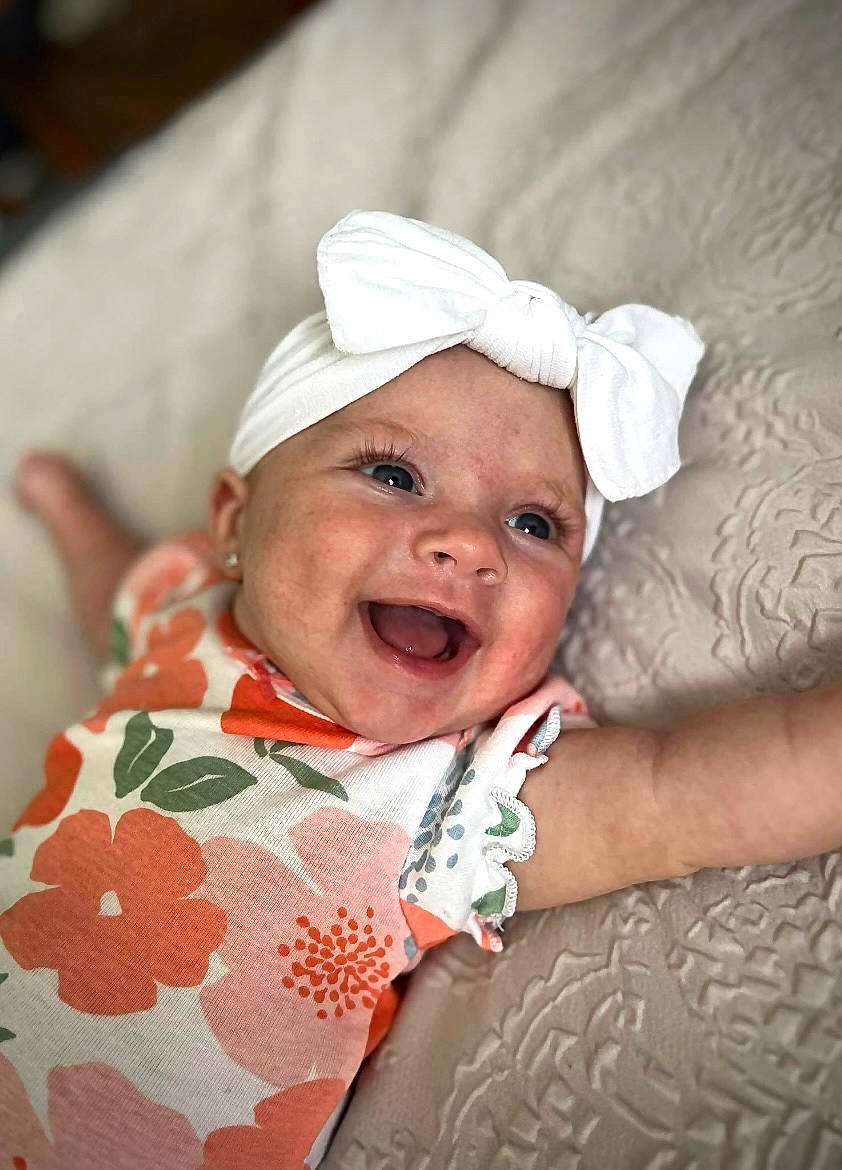 Hadley joined the competition — help win amazing prizes! baby, baby_toddler_clothing, cheek, child, comfort, event, face, facial_expression, flash_photography, fun, gesture, hair_accessory, happy, headgear, headwear, laugh, linens, person, skin, sleeve