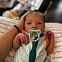 Dutch is registered to the contest to win money with this photo: baby, pacifier, hand, striped_pillow, infant, clothing, person, portrait, newborn, cute, face, skin, sleepwear, resting, babywear, indoor, closeup, newborn_baby, human, comfort
