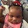 baby, sleeping, bib, pink, red_bow, curly_hair, patterned_pillow, leopard_print, white_shirt, closeup, face, child, infant, resting, cute, adorable, indoor, portrait, peaceful, young