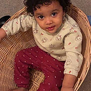 Anora joined the competition — help win amazing prizes! toddler, child, basket, curly_hair, sweater, pants, polka_dot, cat_print, indoor, barefoot, smiling, looking_up, cute, young_child, seated, wicker, floor, cozy, playful, portrait