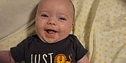 Luella joined the competition — help win amazing prizes! baby, blanket, child, clothing, cute, cute_expression, face, happy, head, human, indoors, infant, lion_graphic, lying_down, onesie, polka_dot_sheet, portrait, small_hands, smiling, text_on_clothing
