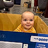 Johnny joined the competition — help win amazing prizes! baby, cardboard_box, child, indoor, dog, chair, floor, furniture, happy, smile, blue_eyes, pet, living_room, casual, curious, person, home, animal, relaxed, cozy