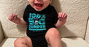 Al joined the competition — help win amazing prizes! baby, black_clothing, chair, child, clothing, cute, eyes, fabric, face, feet, graphic, hands, happy, indoor, onesie, portrait, sitting, smiling, text, texture