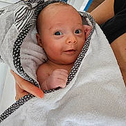 Ambre a rejoint le concours — aidez-le/la à gagner de superbes lots ! baby, newborn, towel, wrapped, hand, person, indoor, blue_eyes, skin, cute, infant, soft, patterned, holding, portrait, human, child, expression, white, cozy
