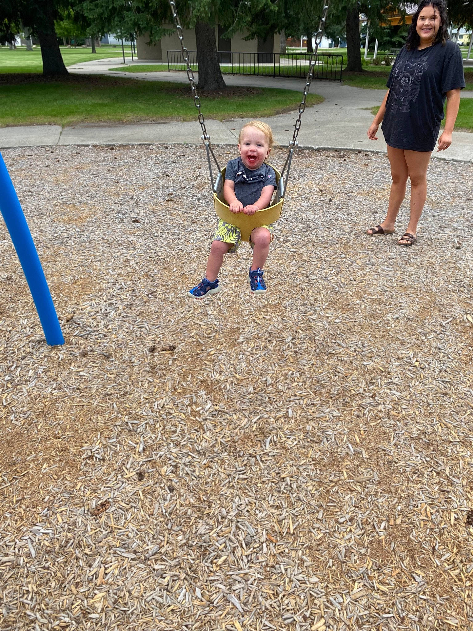 Oliver is registered to the contest to win money with this photo: baby, child, city, electric_blue, fun, grass, joy, leisure, outdoor_play_equipment, people_in_nature, person, plant, play, playground, recreation, shorts, soil, swing, toddler, tree