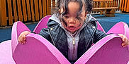 Skylar joined the competition — help win amazing prizes! toddler, child, playground, pink, flower, wood, jacket, hoodie, curly_hair, pigtails, outdoor, fence, bench, play_equipment, hands, looking_down, cute, daylight, casual_clothing, curious