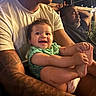 Kiyan Alan is registered to the contest to win money with this photo: baby, child, infant, smiling, happy, portrait, family, adult, outdoor, night, warm_lighting, casual, holding, feet, green_outfit, tattoo, balcony, window, seated, photography
