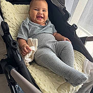 Arofahere participe au concours pour gagner de l'argent avec cette photo : baby, stroller, smiling, gray_clothing, ribbed_leggings, blanket, indoor, natural_light, curtains, child, happy, infant, hand, fabric, face, cheeks, clothing, soft_toy, candid, relaxing