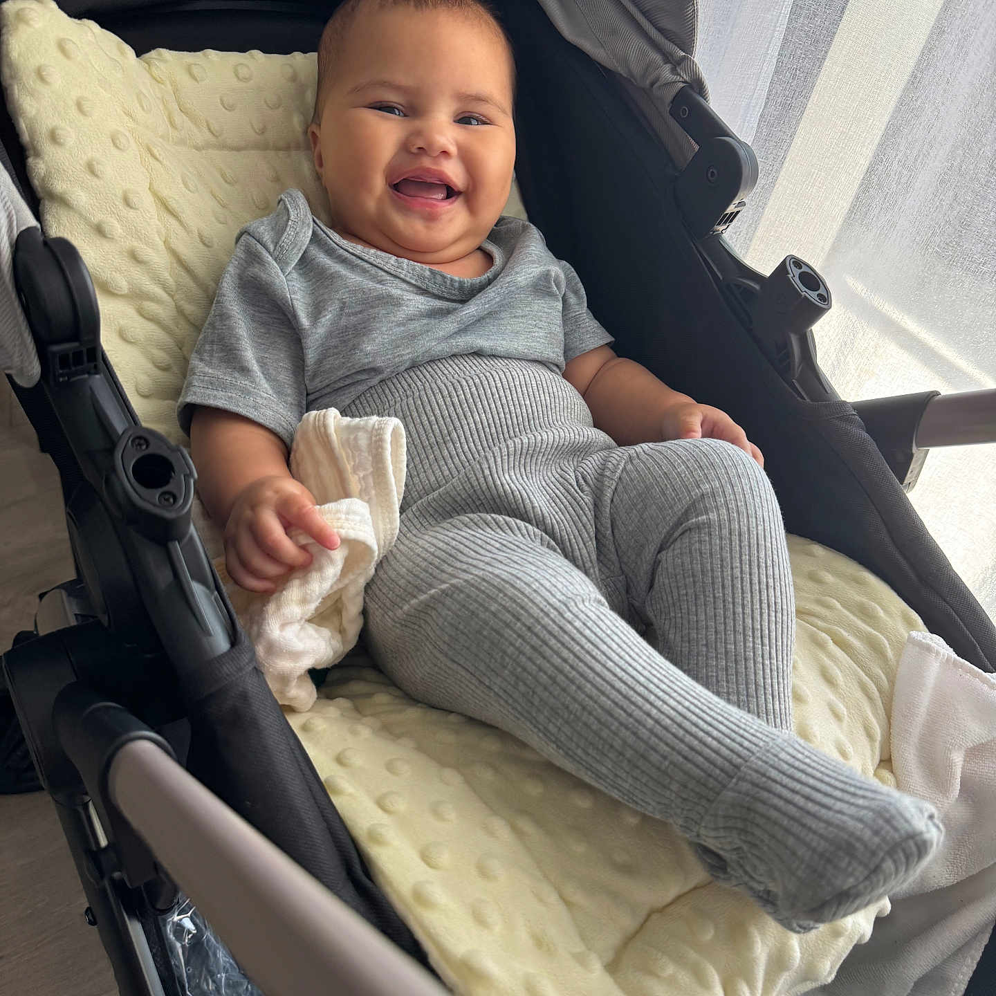 Arofahere participe au concours pour gagner de l'argent avec cette photo : baby, blanket, candid, cheeks, child, clothing, curtains, fabric, face, gray_clothing, hand, happy, indoor, infant, natural_light, relaxing, ribbed_leggings, smiling, soft_toy, stroller