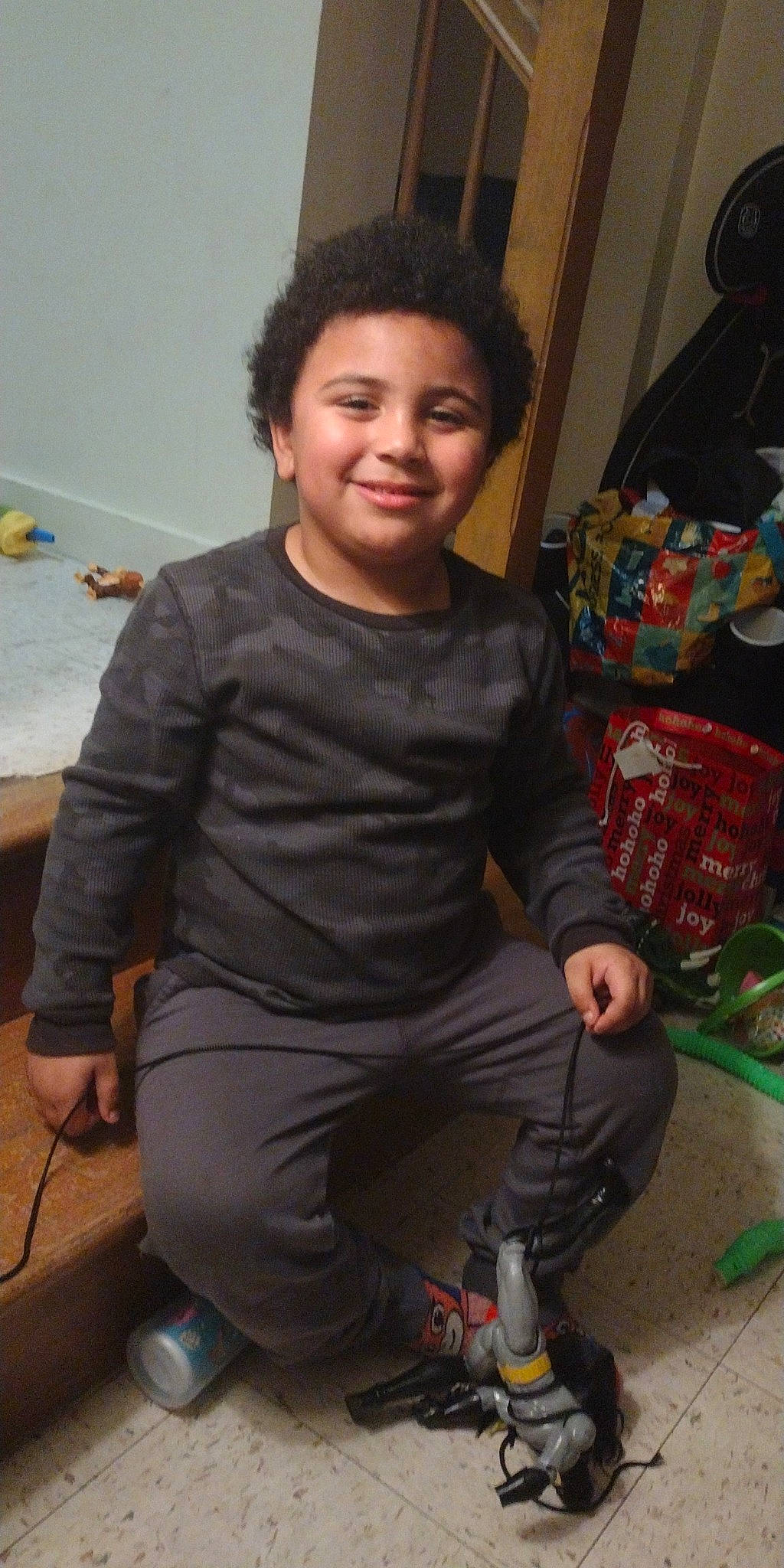 Jayvion is registered to the contest to win money with this photo: black_hair, child, elbow, event, flooring, fun, hairstyle, happy, holiday, human_leg, joy, knee, lap, person, room, shoe, sitting, sleeve, smile, sportswear