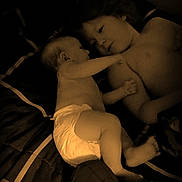 Aaryah is registered to the contest to win money with this photo: baby, infant, child, toddler, siblings, sleeping, bed, bedroom, cuddle, family, diaper, plush_toy, toy, portrait, indoor, dim_lighting, warm_tone, lying_down, affection, snuggling