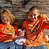 children, baby, siblings, halloween, pumpkin, orange_shirts, outdoor, wooden_background, family, infant, toddler, smiling, portrait, sitting, costume, autumn, seasonal, pumpkin_shirt, newborn, family_photo