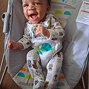 Tristan joined the competition — help win amazing prizes! baby, infant, smiling, laughing, onesie, baby_rocker, patterned_clothing, colorful, indoor, wooden_floor, happy, cute, baby_seat, child, person, footwear, furniture, head, face, playful