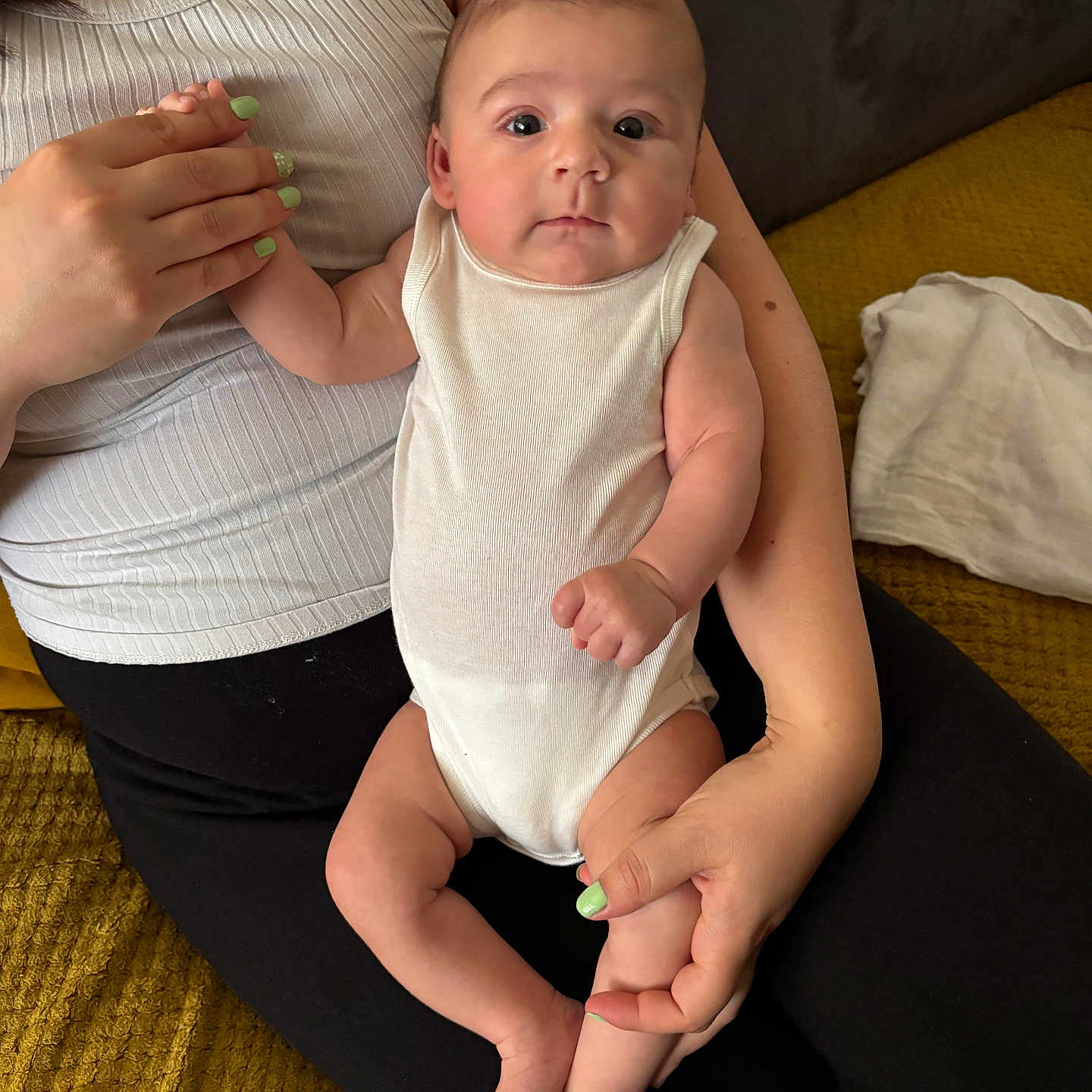 Ezio a rejoint le concours — aidez-le/la à gagner de superbes lots ! adult_hand, baby, casual_clothing, close_up, comfort, fabric, face, feet, fingers, human_body, indoor, infant, legs, nails, person, sitting, skin, textile, white_onesie, yellow_blanket