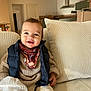 Gaspard a rejoint le concours — aidez-le/la à gagner de superbes lots ! toddler, smiling, child, couch, cushion, blanket, sweater, vest, scarf, indoor, living_room, face, person, happy, cozy, home, furniture, seat, baby, portrait