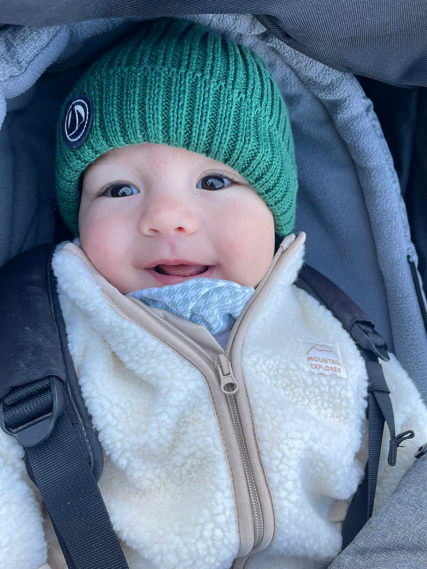 Gaspard a rejoint le concours — aidez-le/la à gagner de superbes lots ! baby, child, smile, green_hat, jacket, zipper, stroller, straps, happy, face, hood, winter_clothing, outdoor, bundle_up, infant, closeup, cute, warm, portrait, babywearing