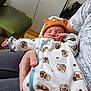 baby, newborn, sleeping, onesie, hat, bear_hat, animal_pattern, person, hand, indoor, chair, clothing, adult, cradle, cozy, cute, resting, infant, soft_fabric, casual
