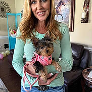 Lola joined the competition — help win amazing prizes! woman, dog, pet, indoor, living_room, smile, casual_clothing, jeans, long_hair, small_dog, pink_harness, holding, portrait, decor, painting, furniture, balloons, wood_floor, happy, home