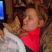 Garfield is registered to the contest to win money with this photo: person, cat, blanket, orange_tabby, couch, indoor, cozy, snuggling, relaxed, warm, furniture, home, portrait, comfort, feline, pet, casual, hair_tie, sweatshirt, living_room