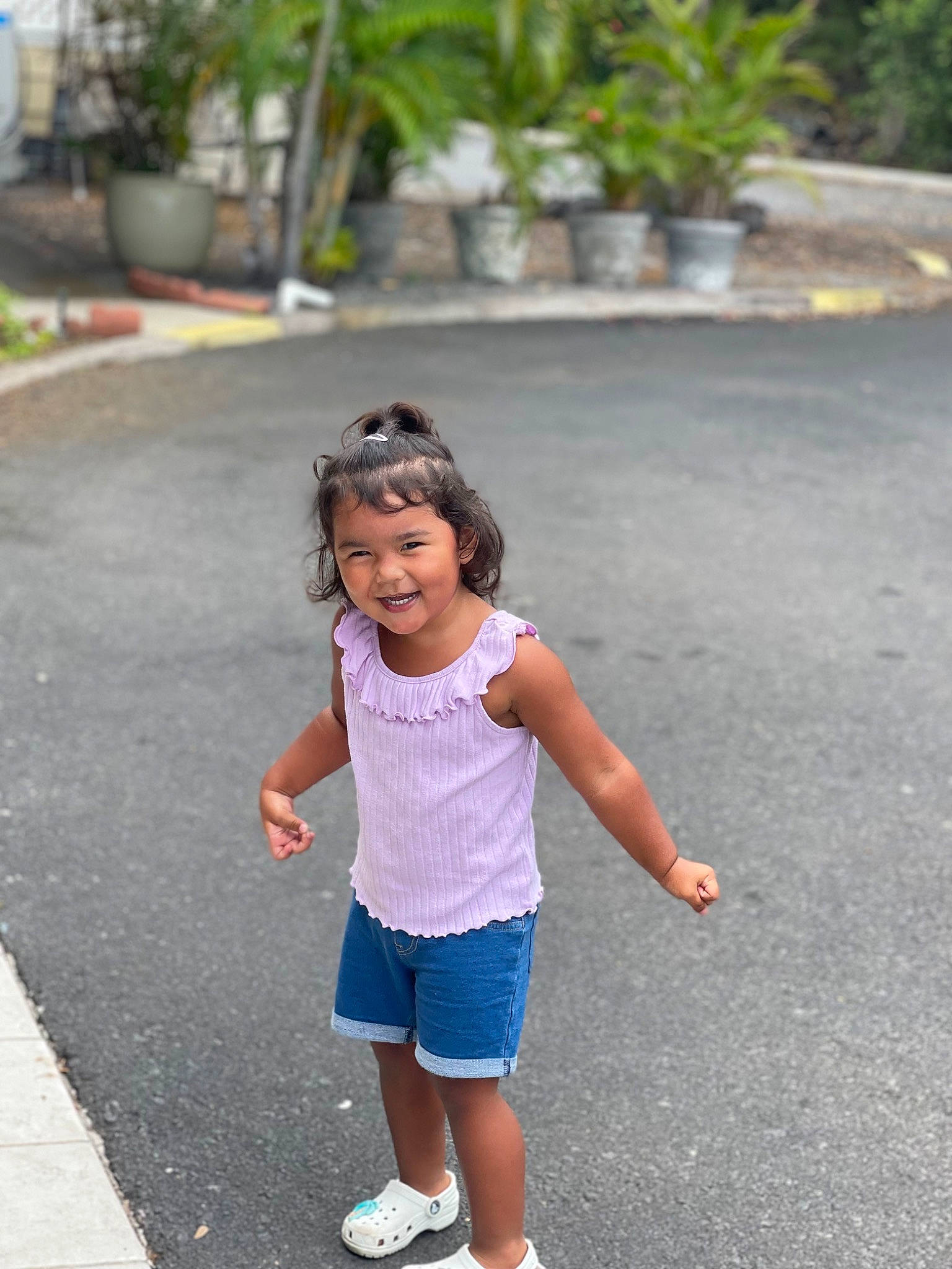 Aiko is registered to the contest to win money with this photo: asphalt, child, flowerpot, footwear, grass, happy, houseplant, human_leg, joy, leisure, person, plant, recreation, road, road_surface, shorts, sidewalk, summer, t_shirt, toddler