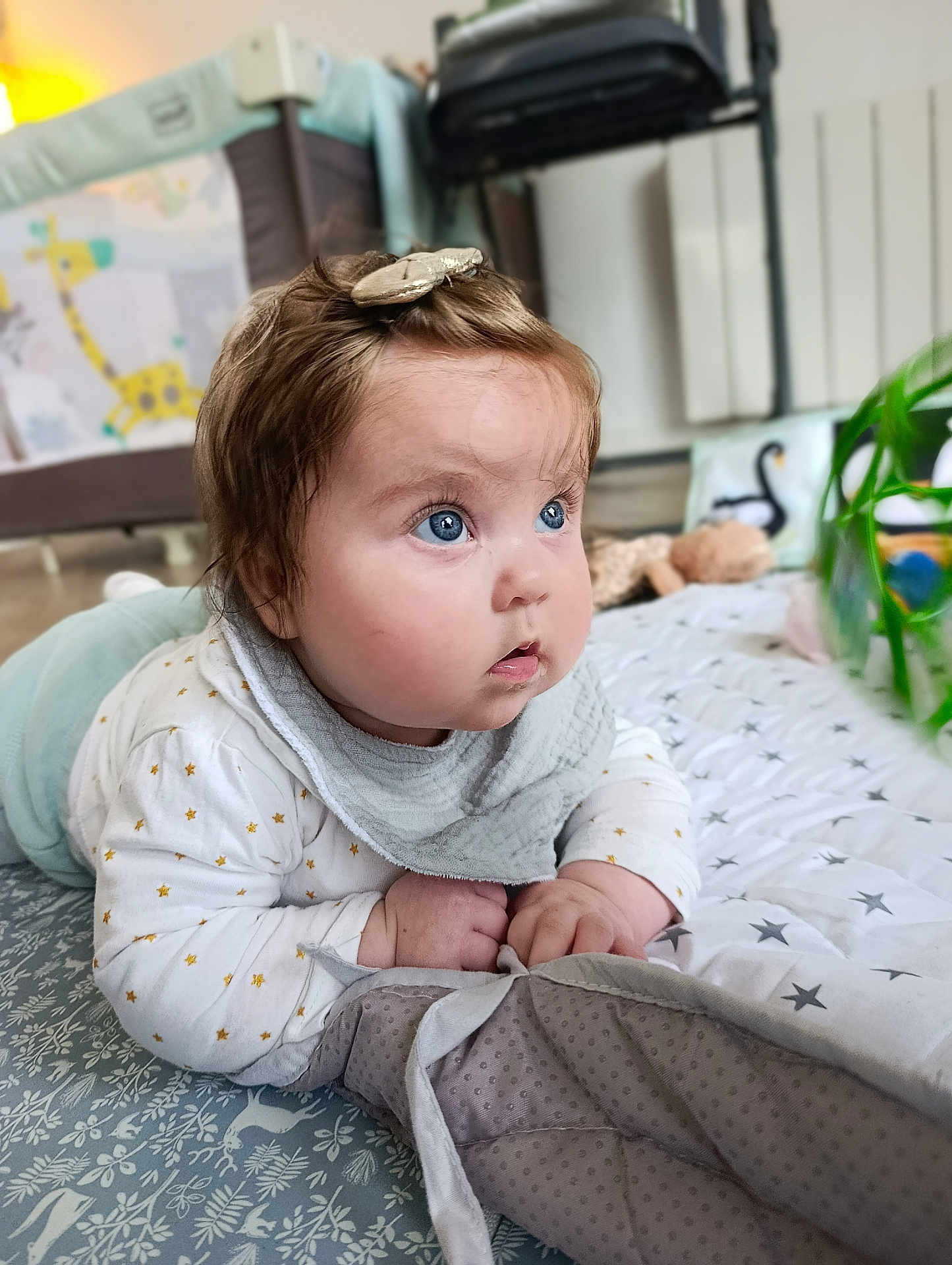Lila participe au concours pour gagner de l'argent avec cette photo : baby, infant, child, blue_eyes, chubby_cheeks, hair_clip, bib, play_mat, plush_toy, playpen, giraffe_pattern, plant, blanket, crawling, indoor, portrait, close_up, star_pattern, clothing, curious_expression