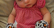 Journey is registered to the contest to win money with this photo: baby, infant, polka_dot, pink_clothing, mittens, animal_print, cushion, blanket, soft_fabric, cute, child, portrait, indoor, comfortable, small_hands, looking, clothing, patterned, seated, toddler