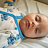 baby, sleeping, onesie, blue_trim, cartoon_characters, polka_dots, bed, white_bed_sheet, infant, face, peaceful, child, soft_lighting, closeup, portrait, resting, cute_clothing, newborn, indoor, cozy