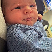 Solann participe au concours pour gagner de l'argent avec cette photo : baby, infant, face, closeup, blue_sweater, knitted_clothing, child, portrait, indoors, resting, newborn, skin, head, expression, cozy, warm_clothing, home, television, soft_light, young
