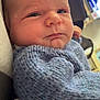baby, infant, face, closeup, blue_sweater, knitted_clothing, child, portrait, indoors, resting, newborn, skin, head, expression, cozy, warm_clothing, home, television, soft_light, young